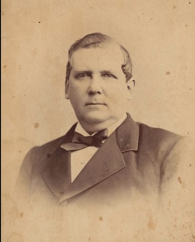 Sepia toned black and white portrait of a man in a suit with a bowtie.