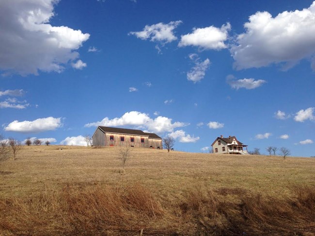 A farmhouse and barn under a blue sky