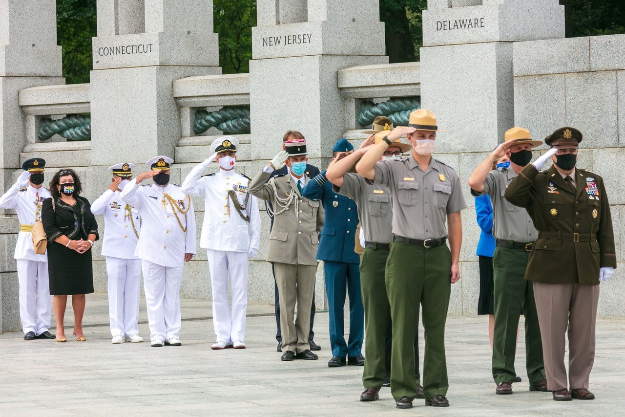 Uniformed men salute the flag.