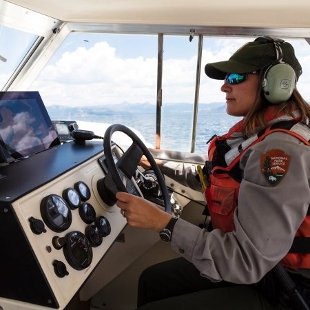 a park ranger driving a boat on a lake