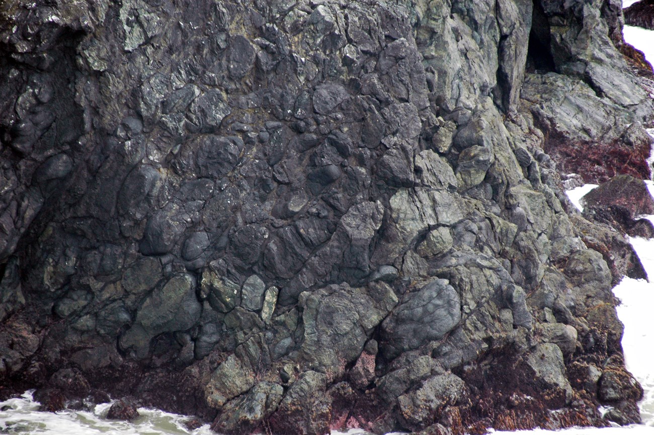 photo of rocky seashore bluff with rounded pillow basalts exposed