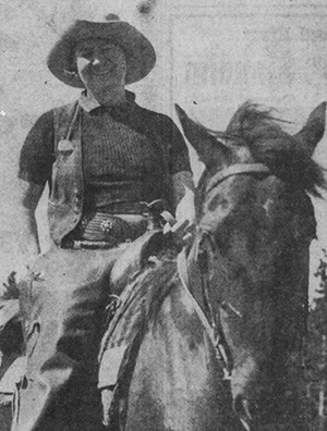 Newspaper photograph of Florene Cassell sitting on a horse and wearing chaps, shirt, vest, cowboy hat, and round guide badge.