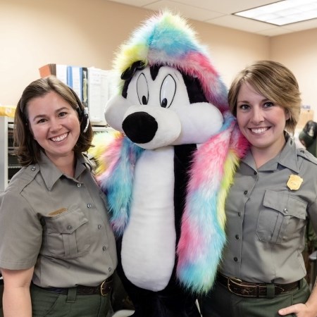 two park rangers smiling with a large stuffed animal in the park's lost and found