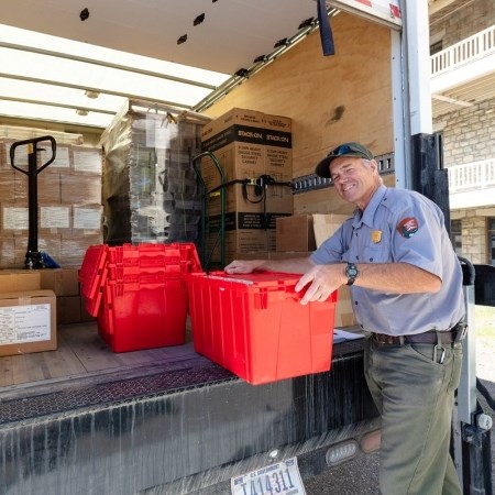 a park ranger unloading packages from the back of a cargo truck