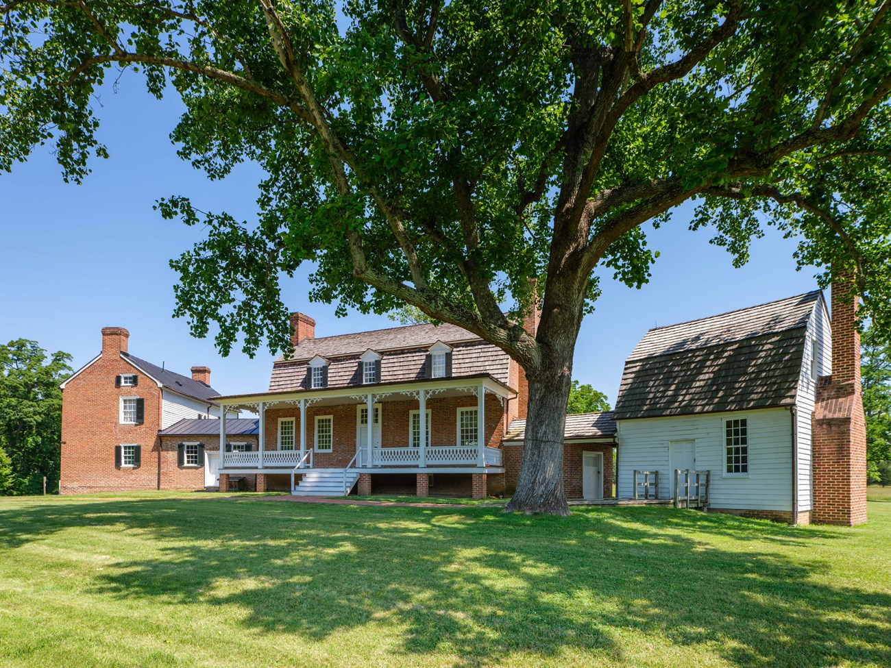 Haberdeventure Red brick two story house with a white front porch and three dormer windows.