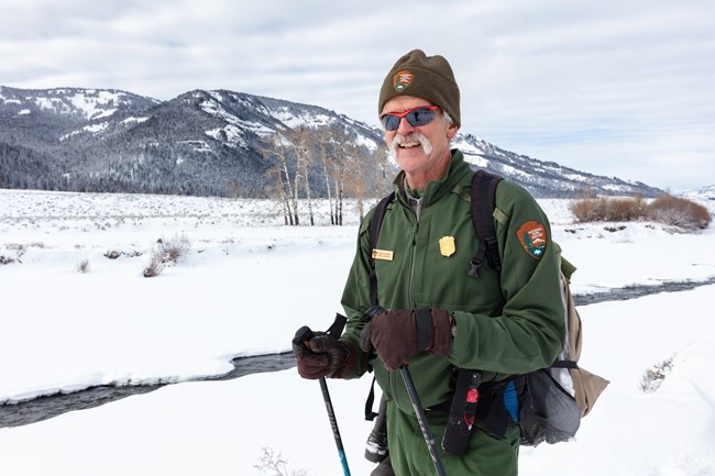 a park ranger carrying bear spray on his hip while out skiing in snow