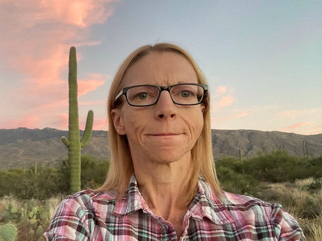 Portrait of Data Manager Helen Thomas in front of Saguaro cactus at sunset