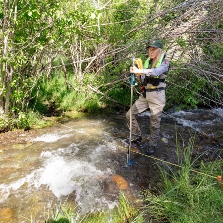 a park ranger using a device in a stream to measure