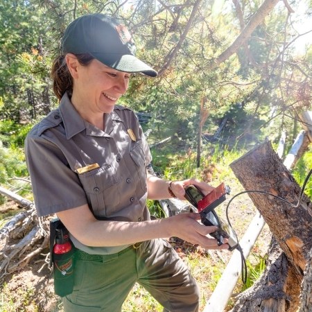 a park ranger holding a small trail counter device