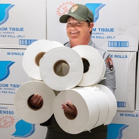 a woman holding up many rolls of toilet paper