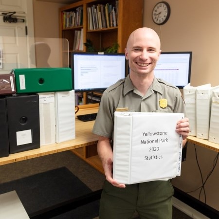 Calculating Entrance Station Stats a park ranger holding up a binder
