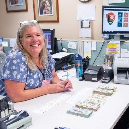 a woman sitting at a desk with money