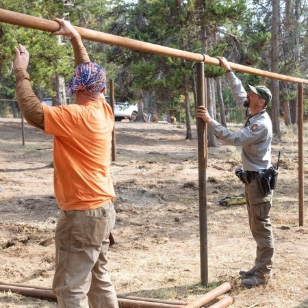 two people building a metal fence