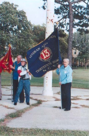 three older men stand holding flags
