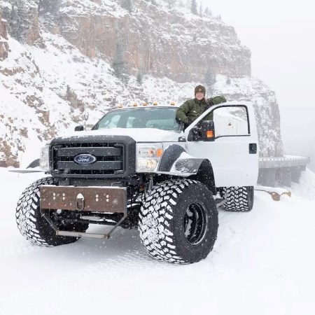 a park ranger standing in the door of a big truck in winter