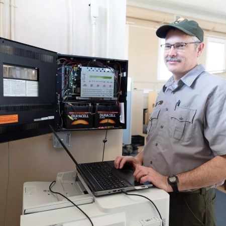 a park ranger with a computer standing next to an alarm system