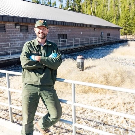 a park ranger leaning against a railing and smiling