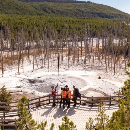 a group of people holding up a camera to photograph a thermal feature