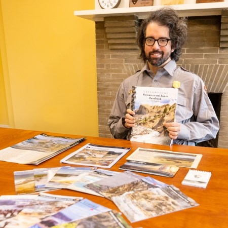 a person wearing a park ranger uniform and sitting at a table filled with brochures