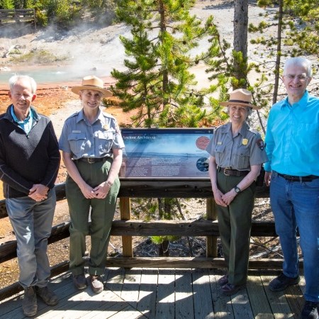 a group of four people standing near a new exhibit sign