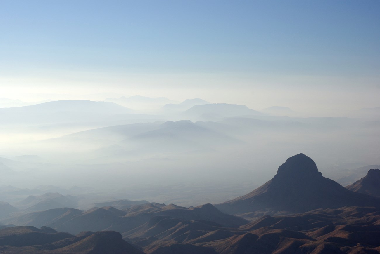 photo of fog shrouded landscape with a tower-like rock peak in the foreground