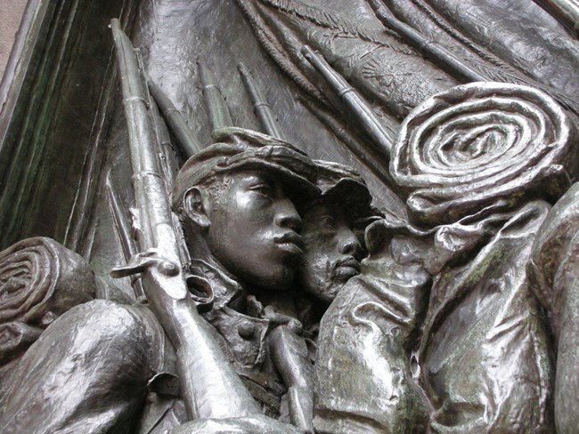 A bronze sculpture of a soldier from the 54th Massachusetts marching with a rifle.