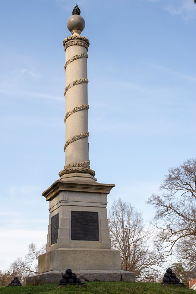 A 20 foot tall narrow stone pillar in a cemetery.