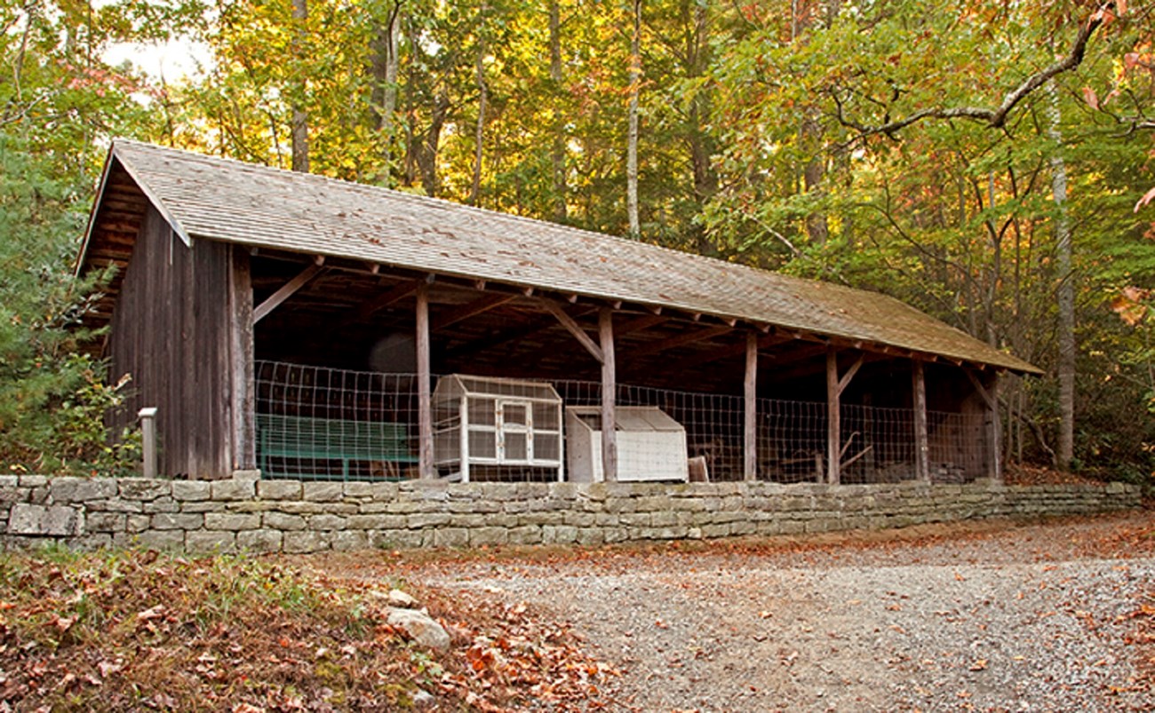 6 woodshed image An open bay wooden shed with a variety of farm and feed equipment stored inside.