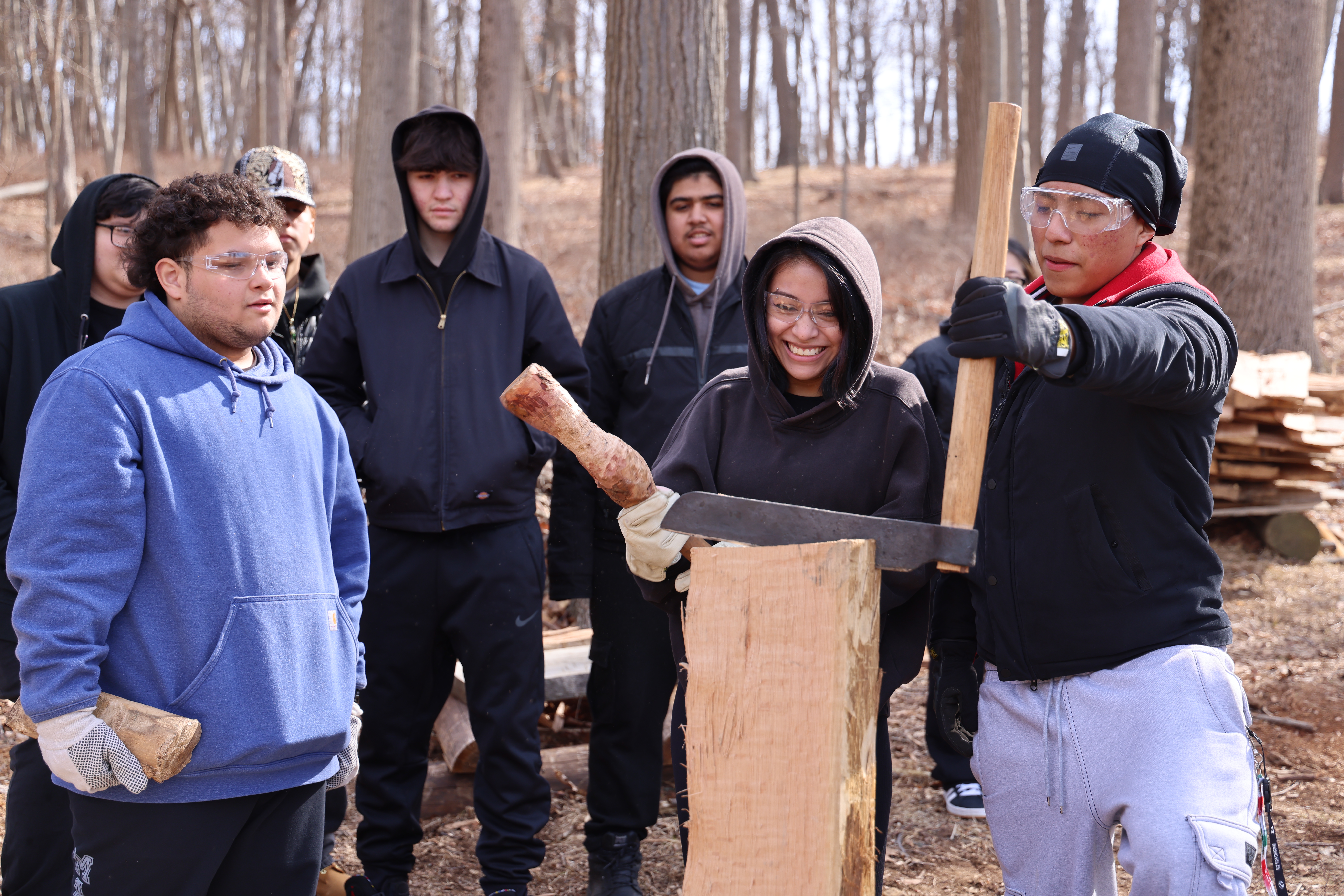 A group of high school students working on reconstructing a log cabin outdoors