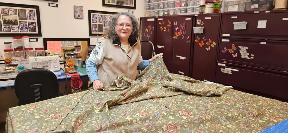 CFH Curtains A woman holds up fabric inside the Fort Vancouver NHS Costume Shop.