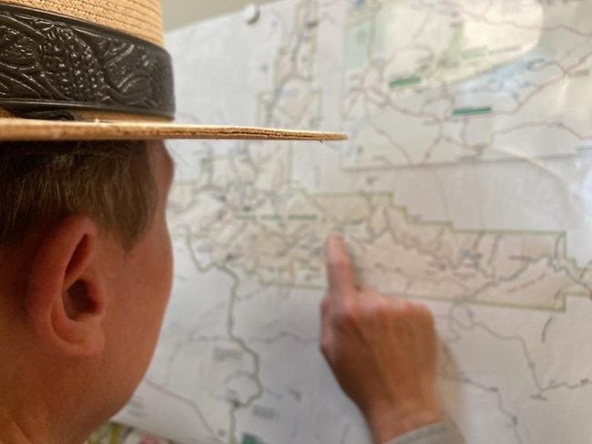 A ranger points to a location on a map.
