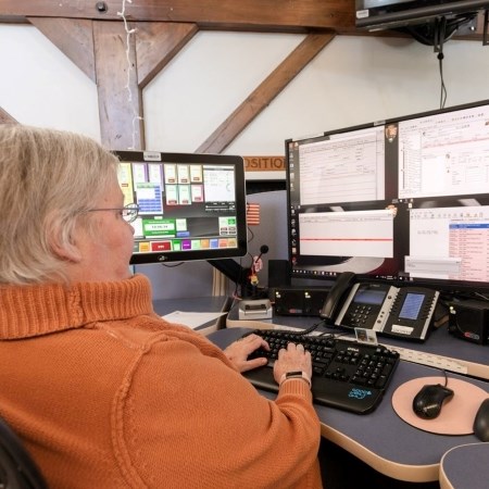 a woman sitting at a desk with multiple computer monitors