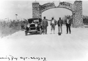 A black and white photo of four men standing in front of the Tamiami Trail