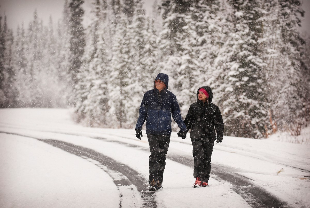 a couple dressed in warm clothes walks through the snow
