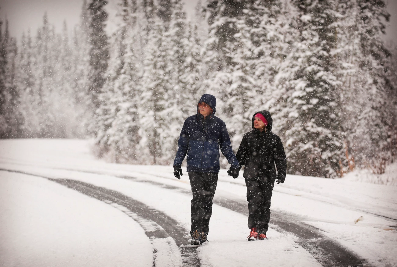 a couple dressed in warm clothes walks through the snow a couple dressed in warm clothes walks through the snow