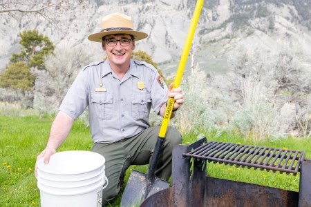 Flood Your Flames a park ranger near a campfire pit