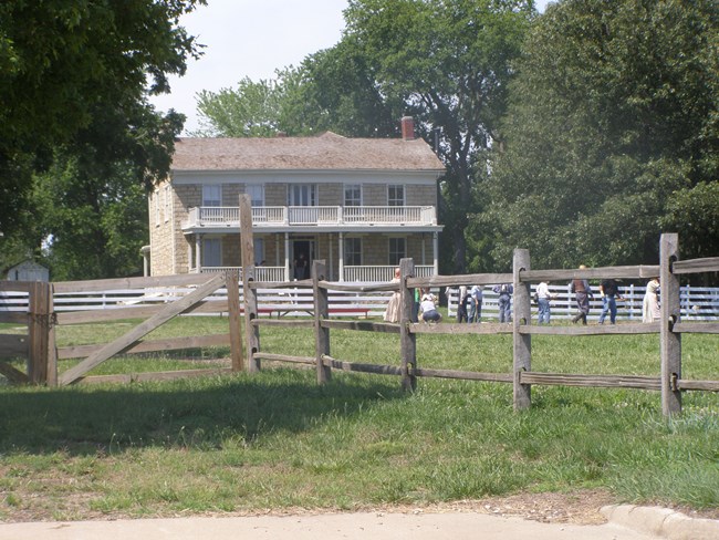 A large yellow, two-story shingled home with a second floor white porch.