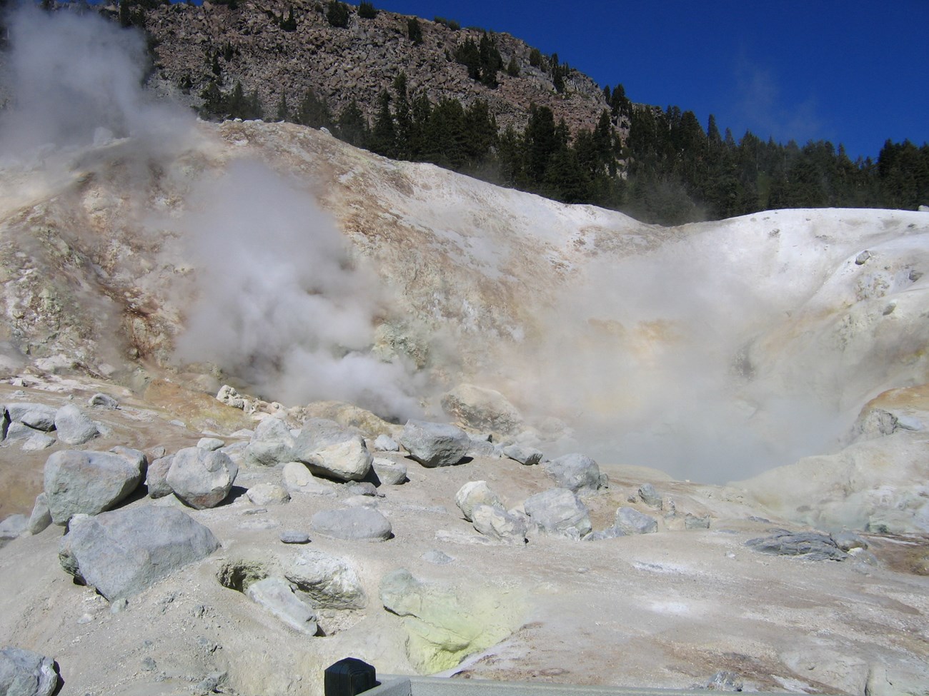 photo of a steaming fumarole surrounded by hydrothermally altered soils