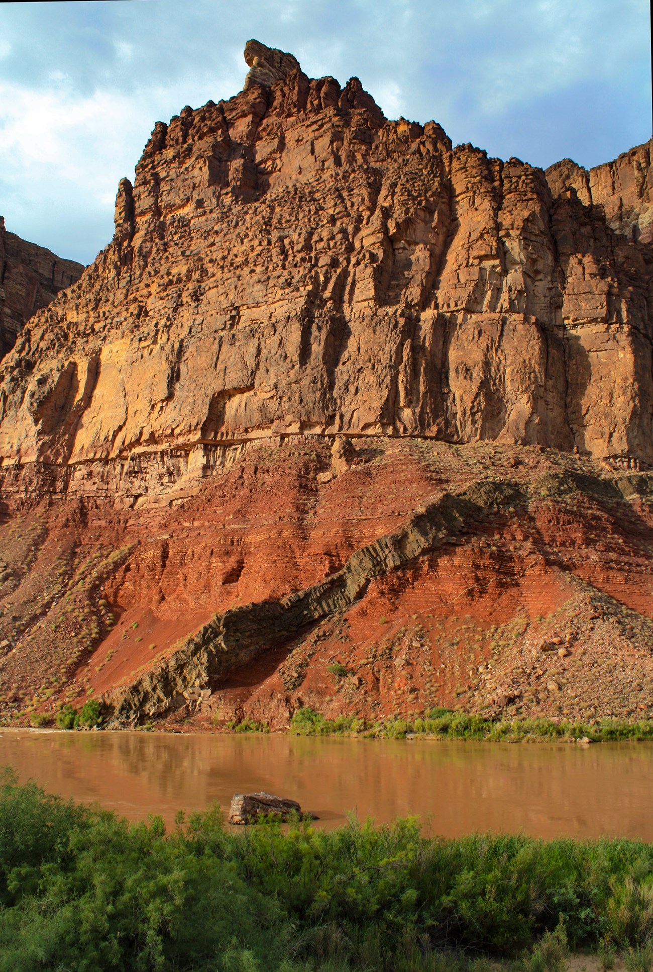 Photo of river side cliffs with a diagonal rock inrusion cross cutting the lower slopes.