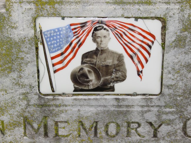 Cameo image of a soldier with an American flag flying over him.
