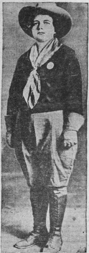 Newspaper photo of Mrs. Ricard in wearing breeches, boots, shirt, gauntlets, kerchief, cowboy had, and a round guide badge.
