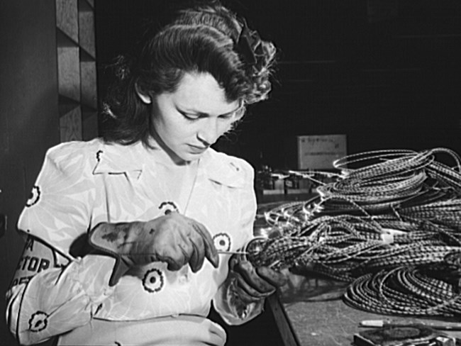 A woman sitting at a table connecting wires.