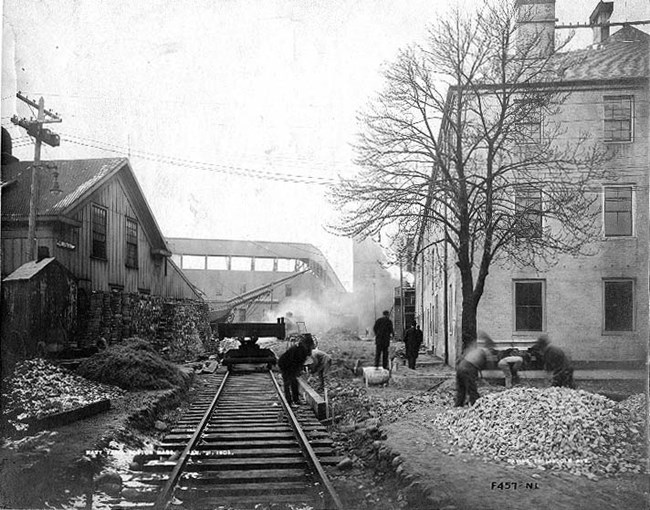 scene of workers building a railroad track between two buildings