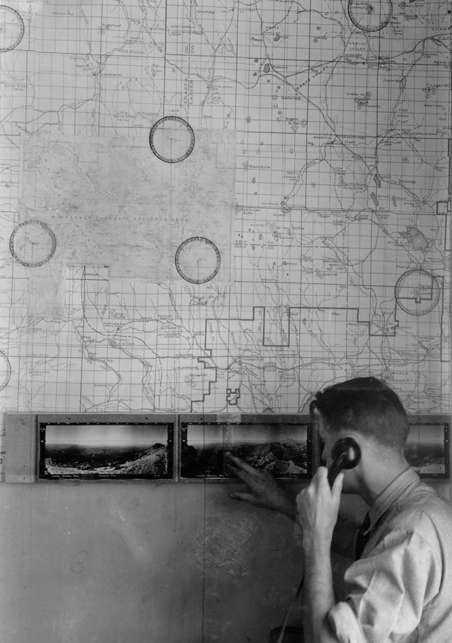 Using panoramic photos A man on the telephone points to panoramic photos below a large map on a wall.