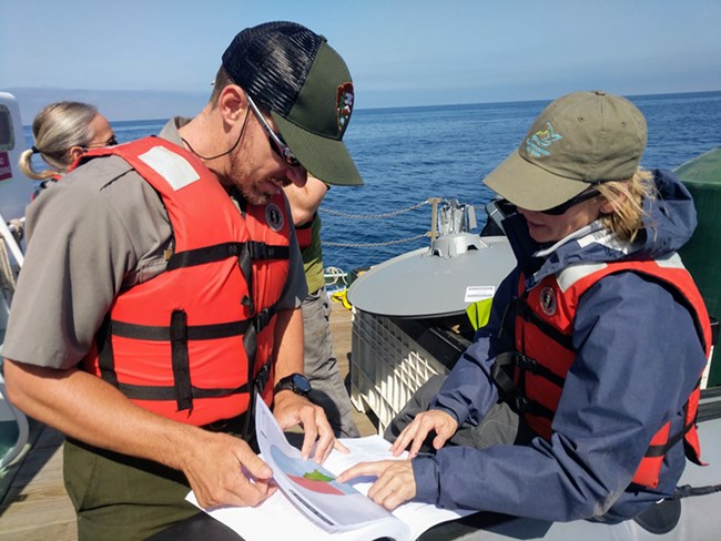 lt= ranger wearing life jacket with visitor looking at map