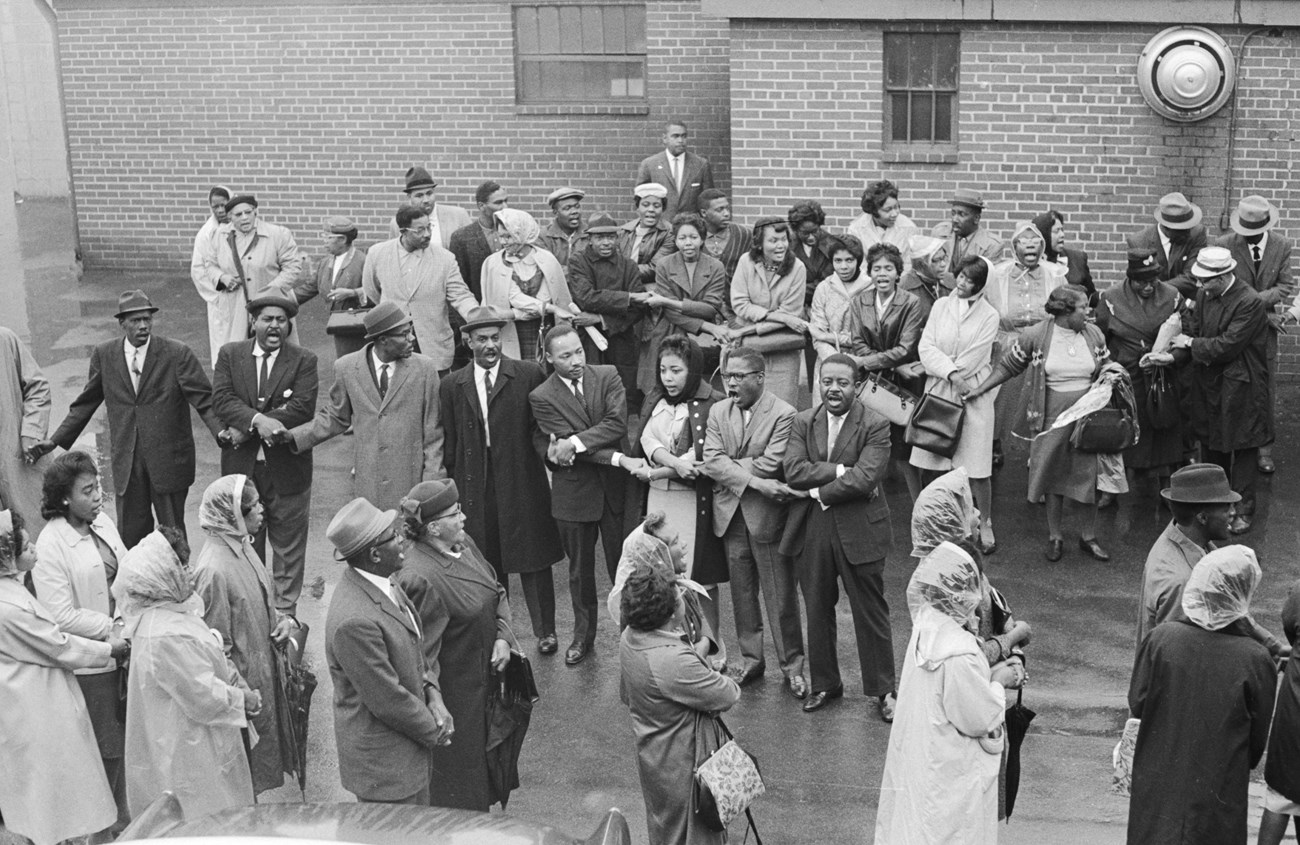 Civil rights activists in coats and rain gear sing during a protest in Birmingham, AL.