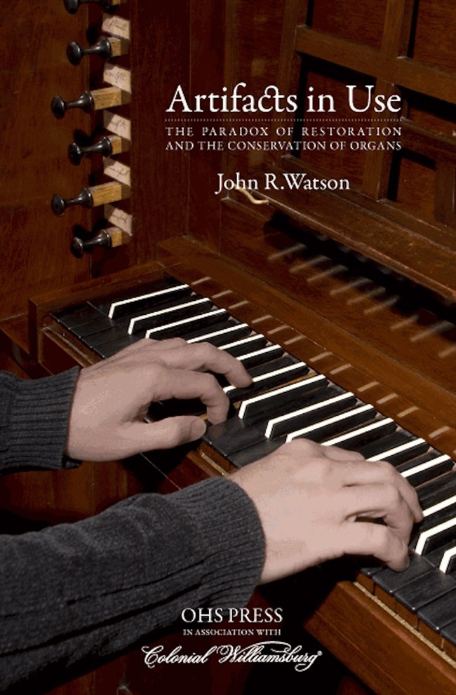Book: Artifacts in Use by John R. Watson. Cover: Hands playing a piano. Book: Artifacts in Use by John R. Watson. Cover: Hands playing a piano.