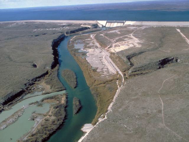 Amistad Dam An aerial view of a river meeting a dam and the reservoir beyond it