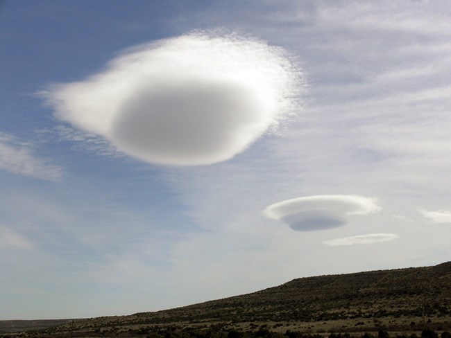 Lenticular clouds at Amistad National Recreation Area Two large circular clouds in the sky over a desert hill