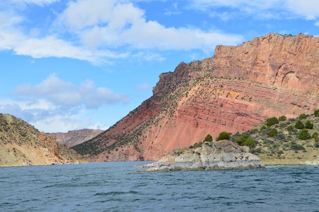 Large red and tan rock formations jut into a water body